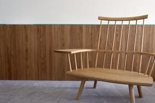 a wooden chair sitting in front of a wooden wall at 滔々 御崎 二階の宿 toutou Onzaki Nikai no Yado in Kurashiki