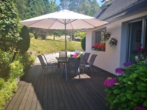 a patio with a table and chairs and an umbrella at Joelle et Hans B&B in Hôpital-Camfrout