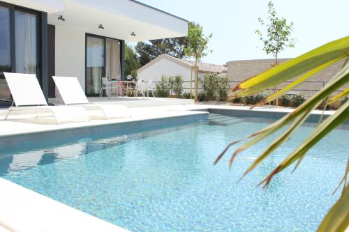 a swimming pool with chairs and a house at Villa Sunny Garden in Barbat na Rabu