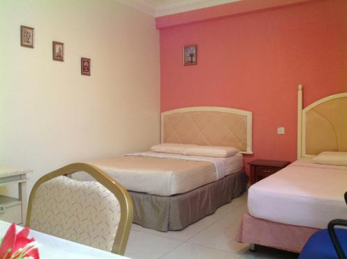 a hotel room with two beds and red walls at Hotel Morning Glory in Kudat