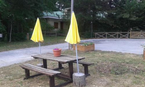 a picnic table with two yellow umbrellas on it at La Pineta di Giove - Casa Lory in Campo di Giove