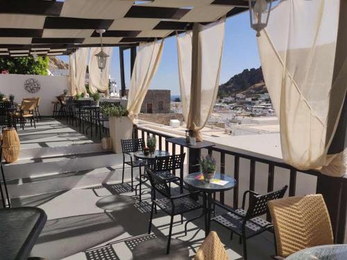 a patio with tables and chairs on a balcony at Xenones Lindos in Líndos