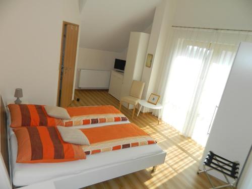 a bedroom with a bed with orange and orange sheets at Gästehaus Borniger in Gau-Weinheim