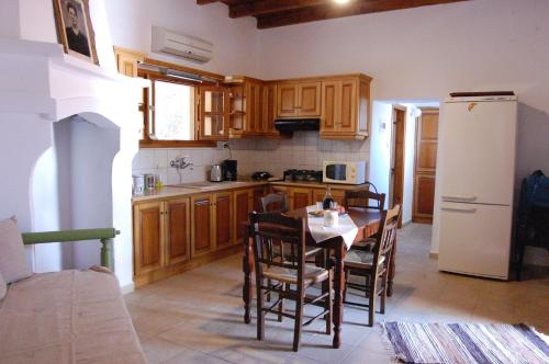 eine Küche mit einem Tisch und einem weißen Kühlschrank in der Unterkunft Old Winery House in Kolimvárion