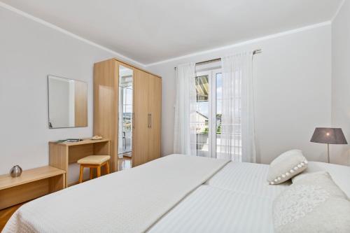 a white bedroom with a large bed and a window at Apartman Ivan in Malinska