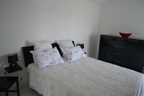 Schlafzimmer mit einem Bett mit weißer Bettwäsche und Kissen in der Unterkunft L'Ostalòt in Saint-Vincent-de-Tyrosse