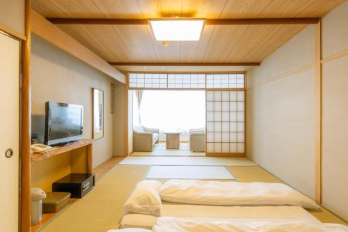 a japanese room with a bed and a television at Kameya Rakan in Ito