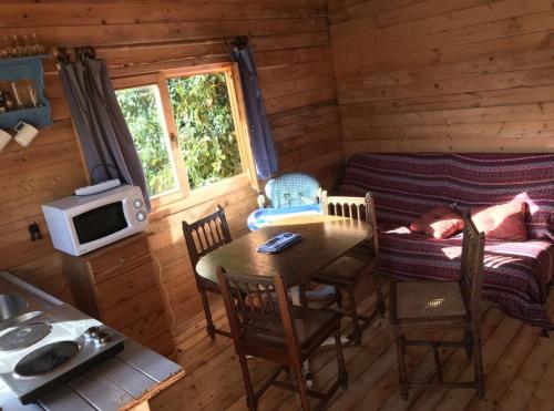 une chambre avec une table et un canapé dans une cabine dans l'établissement un Chalet avec jardin à 1km de la mer, à Saint-Froult