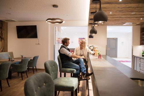 a man and woman sitting at a bar in a room at Hotel Räucherhansl in Loiching