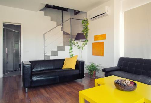 a living room with a black leather couch and a yellow table at TOLETUM low cost LOFTS diáfanos o 2dormitorios PARKING Municipal Gratis al aire libre a 100m in Toledo