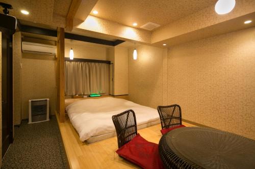 a bedroom with a bed and a table and chairs at Hotel Kilala (Adult Only) in Koriyama
