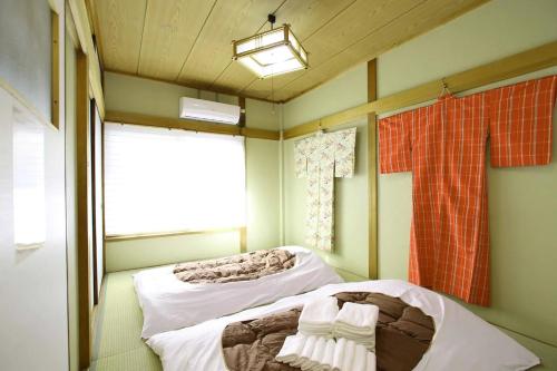 two beds in a room with a window at Masaru House in Osaka