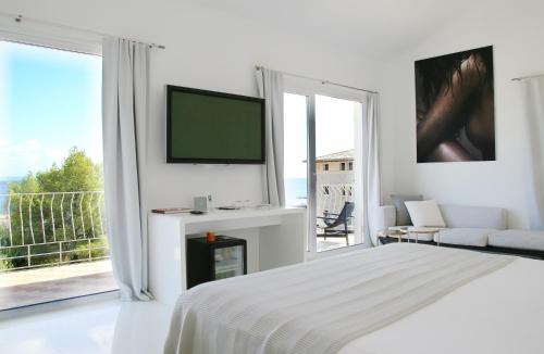 a white bedroom with a flat screen tv and a bed at Hotel Zhero in Cas Catala