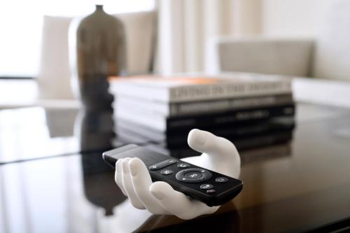 a hand in white gloves holding a remote control on a table at Vida Emirates Hills in Dubai