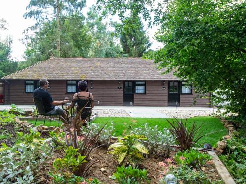 two people sitting in a garden in front of a house at The Withies Inn in Godalming