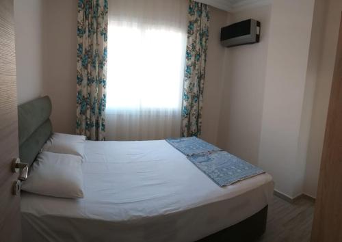 a bedroom with a large bed with a window at GÜMÜLDÜR ÇALIŞKAN APART 1 in Gumuldur