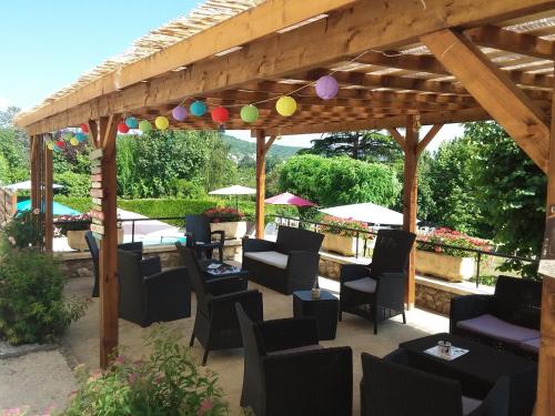 a patio with chairs and tables under a wooden pergola at Hotel Belle Vue in Souillac