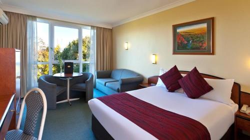 a hotel room with a large bed and a chair at Alpine Motor Inn in Katoomba