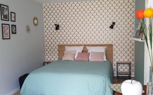 a bedroom with a blue bed with pink and white pillows at Clos Charmille in Meaulne