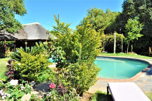 a swimming pool in a garden with flowers at Natwange Backpackers in Lusaka