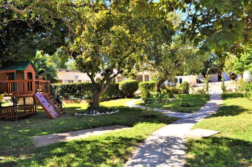 a playground in a yard with a tree and a sidewalk at Natwange Backpackers in Lusaka