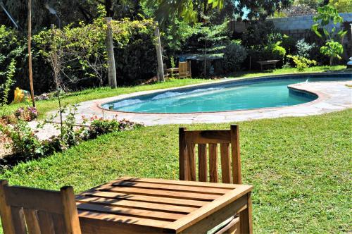 a wooden chair sitting in the grass next to a swimming pool at Natwange Backpackers in Lusaka