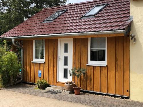 a wooden house with a red roof and windows at Ferienwohnung Niesky in Niesky