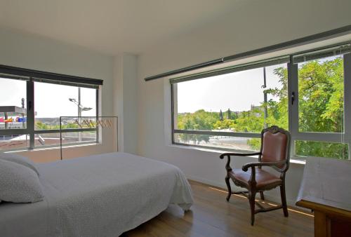 a bedroom with a bed and a chair and windows at TOLETUM low cost LOFTS diáfanos o 2dormitorios PARKING Municipal Gratis al aire libre a 100m in Toledo
