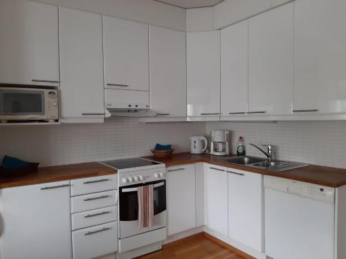 una cocina blanca con armarios blancos y fregadero en Apartment Asemakatu 20, en Kuopio
