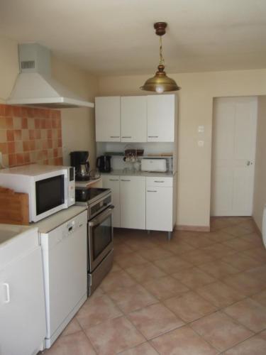 une cuisine avec des armoires blanches et un micro-ondes dans l'établissement JOLIE MAISON ANCIENNE RENOVEE PRES DU ZOO BEAUVAL TOUT CONFORT, à Selles-sur-Cher