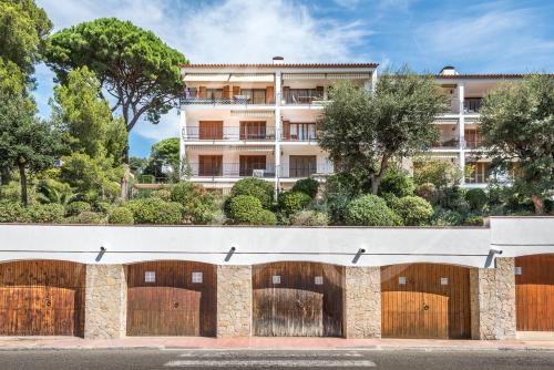 a building with four garage doors with trees at Antora B, by SeaMount Rentals in Calella de Palafrugell