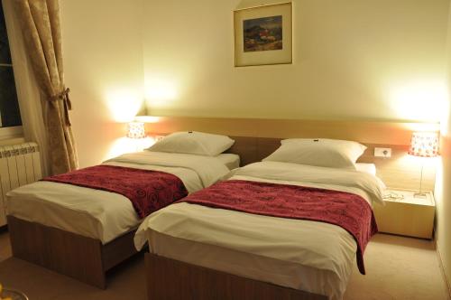 two beds in a hotel room with lights on at Apartments Legacy in Belgrade