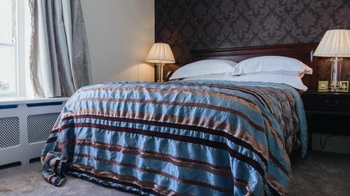 a bedroom with a bed with a striped blanket at Wildes Inns in Chesterfield