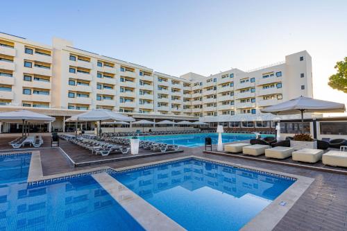 a hotel swimming pool with chairs and umbrellas at Albufeira Sol Hotel & Spa in Albufeira