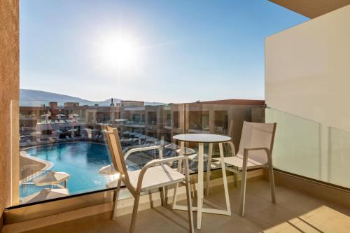a balcony with a table and chairs and a pool at White Olive Elite Laganas in Laganas