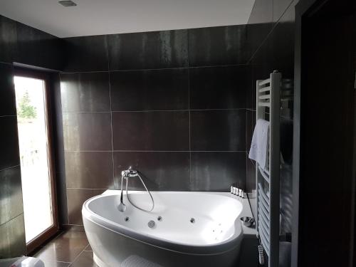 a bath tub in a bathroom with a window at Rezidencija Grįžulo ratai in Sasnava
