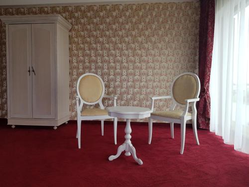 a room with two chairs and a table and a cabinet at Rezidencija Grįžulo ratai in Sasnava