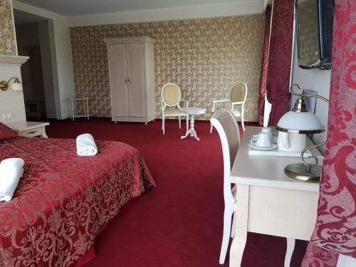 a hotel room with a bed and a table and chairs at Rezidencija Grįžulo ratai in Sasnava