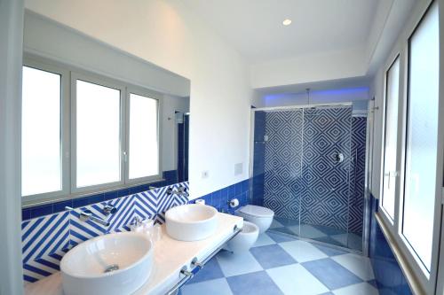 - une salle de bains bleue et blanche avec deux lavabos et une douche dans l'établissement Maison Tonina Sorrento Coast, à Sant'Agnello