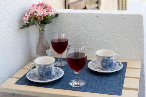 two glasses of red wine and two cups on a table at Apartment Medusa in Risan