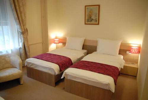 a hotel room with two beds and a chair at Apartments Legacy in Belgrade