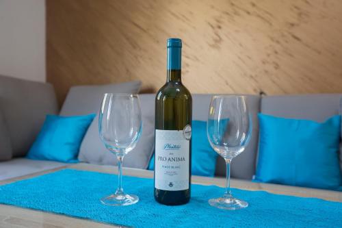 a bottle of wine and two wine glasses on a table at Apartment Medusa in Risan