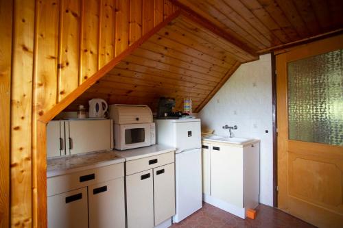 a kitchen with white appliances and a wooden ceiling at Szabó Vendégház in Siklós