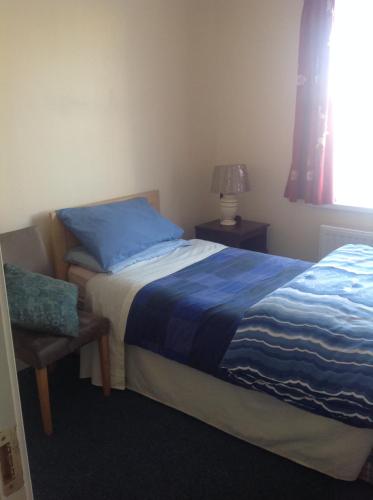 a bedroom with a bed with a blue blanket and a window at Harbour House in Tullamore