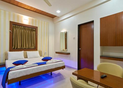 Schlafzimmer mit einem Bett, einem Tisch und einem Schreibtisch in der Unterkunft Hotel Ganeshratna Executive in Kolhapur