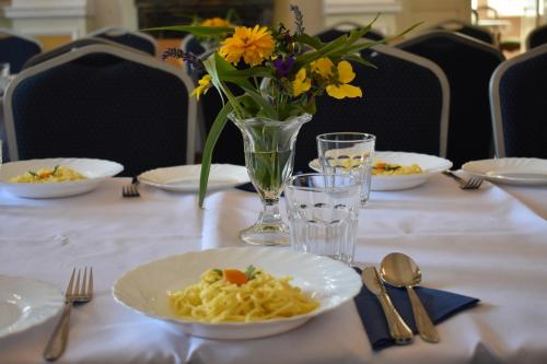 a table with plates of pasta and a vase of flowers at Eden in Wisełka