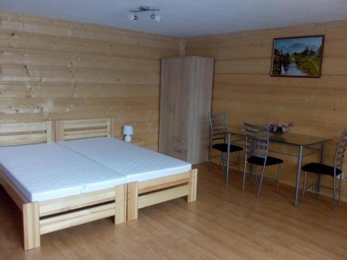 ニエジツァ・ザメクにあるDrewniane pokoje w Niedzicyのベッドルーム1室(ベッド1台、テーブル、椅子付)