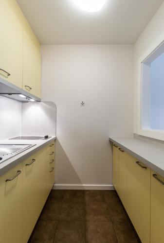 an empty kitchen with yellow cabinets and a window at Residence Lastei in San Martino di Castrozza