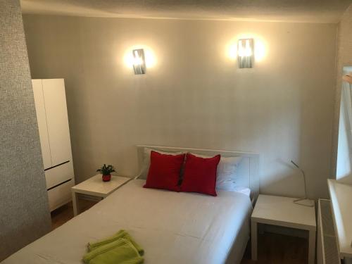 1 dormitorio con 1 cama con 2 almohadas rojas en Saules Kvartāls, en Ventspils