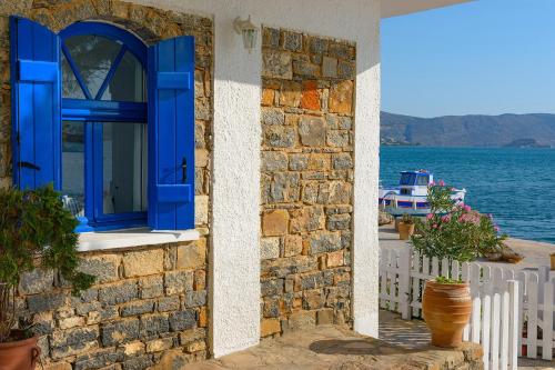 a blue window on a stone building with a view of the water at Eleftheria Sea Side Traditional House in Elounda